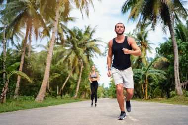 Genç adam ve kadın palmiye ağaçları altında çalışan.