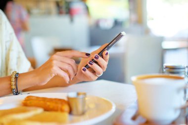 Kadın sosyal medya mesaj cep telefonu elele. İş kadını Kahvaltı.