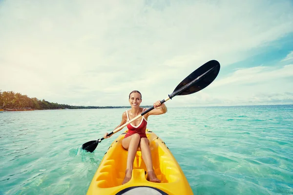 在热带湾附近划海皮艇的年轻女子 — 图库照片