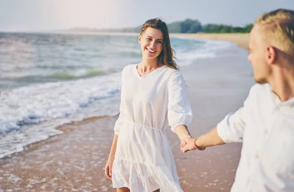 Young loving couple walking together by the sand beach enjoying sea