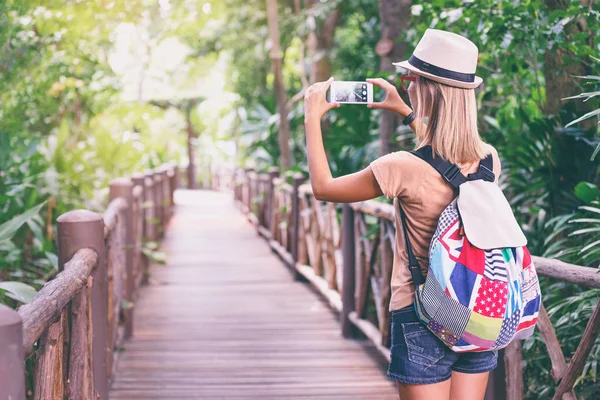 若い女性は ジャングルの中でスマート フォンで写真を撮る — ストック写真