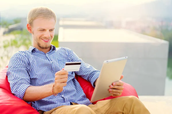 Przystojny Młody Człowiek Przy Użyciu Komputera Typu Tablet Posiadający Karty — Zdjęcie stockowe