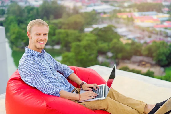 年轻英俊的人工作在笔记本电脑 而坐在屋顶上 — 图库照片