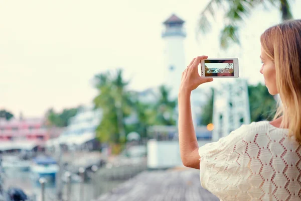 若い女性が海岸沿いに歩きながらスマート フォンで写真を撮影 — ストック写真