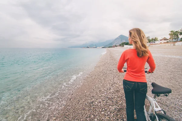 美丽的年轻女子走近海与自行车对天空背景 — 图库照片