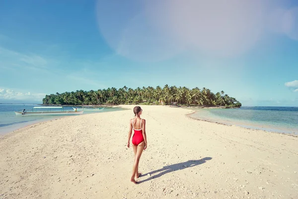 在美丽的热带白色沙滩上走在红色泳装的年轻妇女的后面看法 — 图库照片