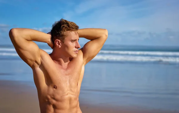 Handsome and strong young man tanning on the beach.