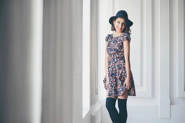 ドレスと帽子立っている窓の近くの美しい若い女性 — ストック写真