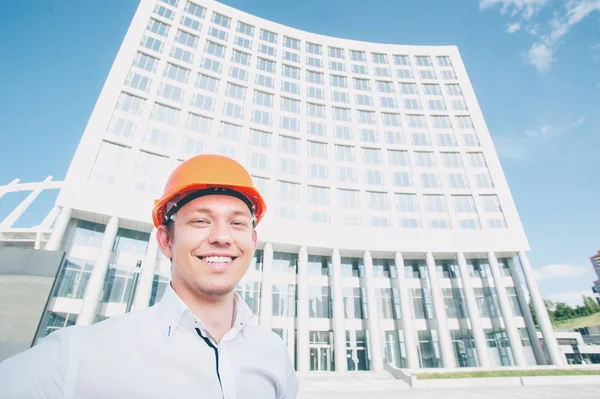 建築構造物に対して屋外で立ってヘルメットでハンサムな笑顔の若い男 — ストック写真
