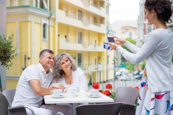 Pareja Mediana Edad Abrazándose Cafetería Mientras Hija Adulta Fotografiándolos Teléfono —  Fotos de Stock