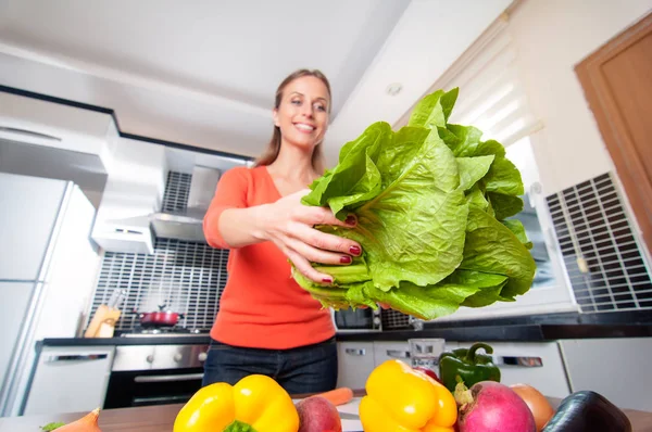 Wide angle view of young caucasian woman making healthy food standing happy smiling in kitchen holding salad