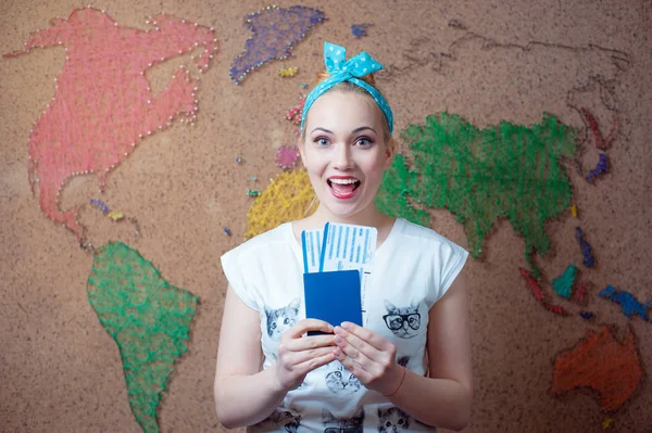 パスポートと世界地図で壁に立っている間航空券を保持している若い幸せな女 — ストック写真