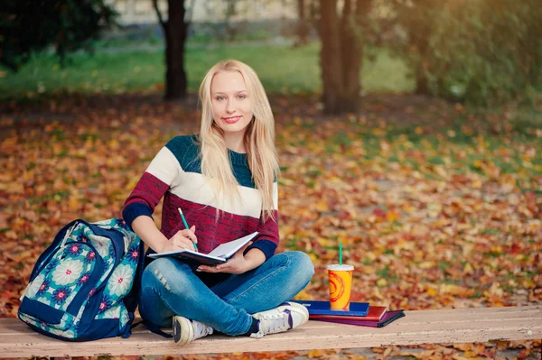 Krásná Mladá Studentka Psát Něco Notýsku Zatímco Sedí Podzimním Parku — Stock fotografie