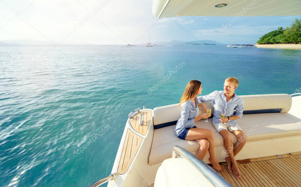 Young loving couple sitting on the sofa on the modern yacht deck