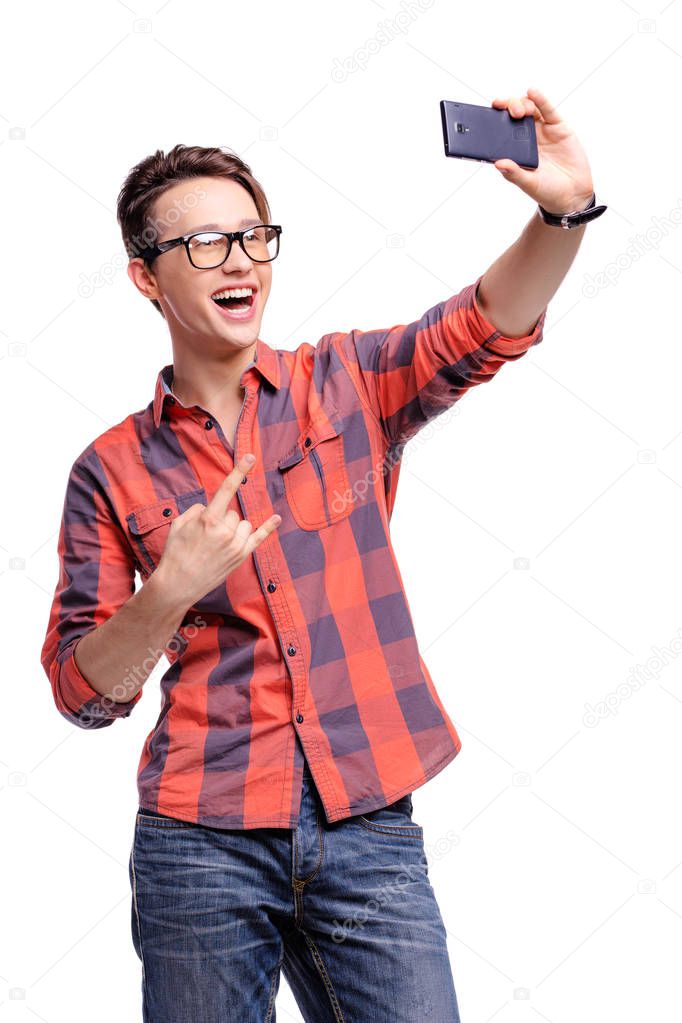 Studio portrait of happy handsome young man taking selfie on his smart phone