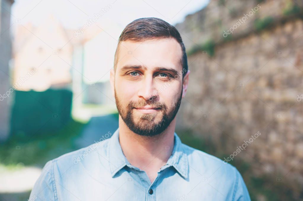 Close up portrait of Attractive young bearded man looking at camera outdoors