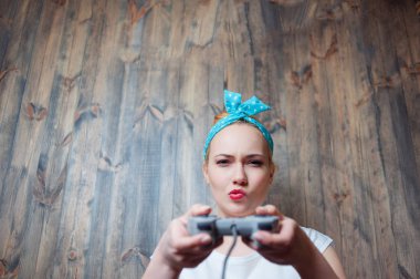 Ahşap duvar karşı konsol joystick ile oynayan genç sarışın kadın.