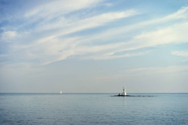Sakin deniz ve ada beyaz deniz feneri.