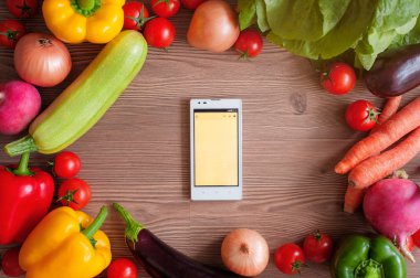 Taze organik sebze ve ahşap arka plan üstünde belgili tanımlık merkez içinde smartphone