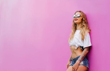 Pembe duvara poz şortlu genç oldukça mutlu kadın.