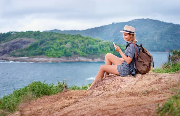 Młoda Kobieta Aparatu Plecak Pomocą Smartfona Widokiem Morze — Zdjęcie stockowe