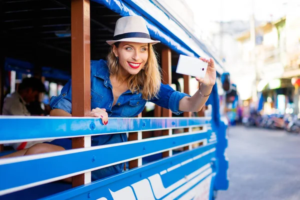 伝統的なタイのバスで楽しむ旅行をスマート フォンで写真を撮る帽子の若いきれいな女性 — ストック写真