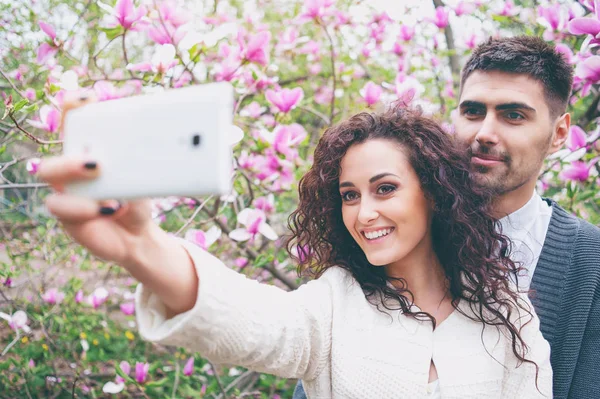 Mladý Usměvavý Milující Pár Pořizování Selfie Stoje Kvetoucí Zahradě — Stock fotografie