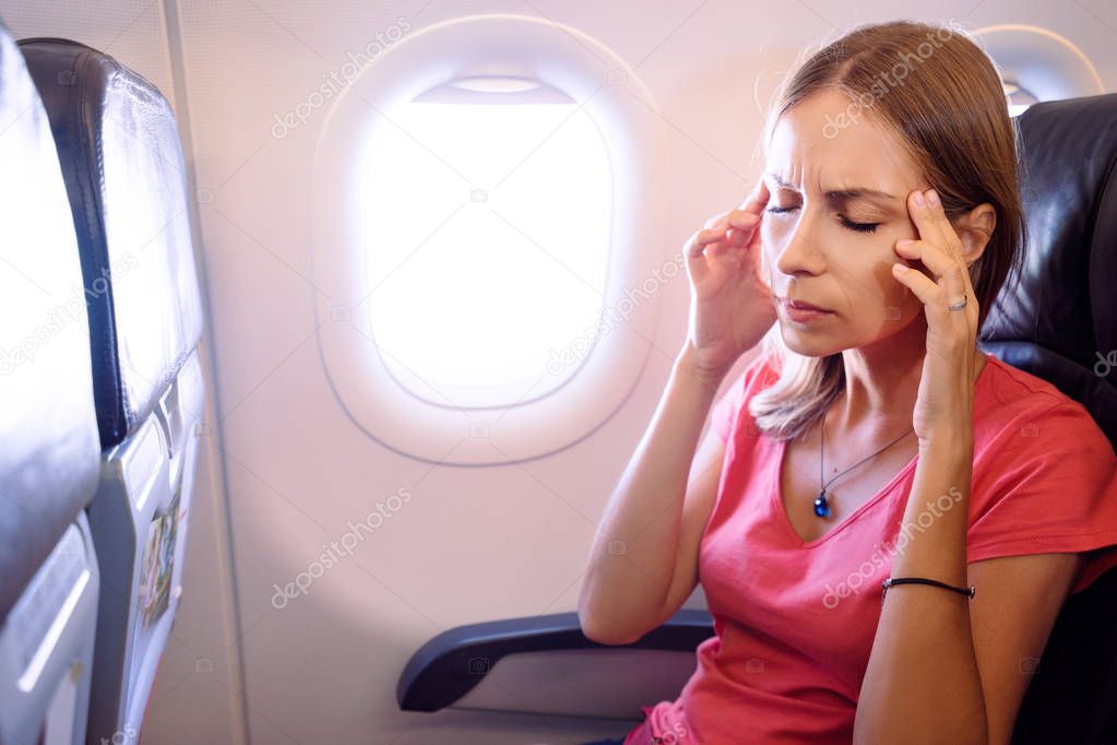 Fear of flying woman in plane airsick with stress headache and motion sickness or airsickness.