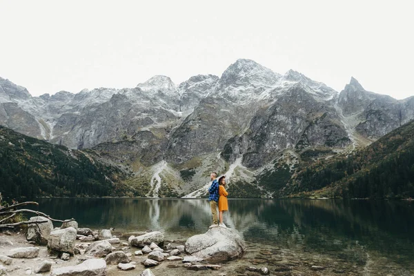 Lovely couple travelling together in the mountains, walking around the lake Morskie oko in Tatry. Amazing girl in yellow dress. Stunning view.