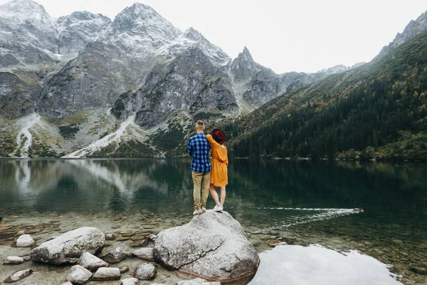 Lovely couple travelling together in the mountains, walking around the lake Morskie oko in Tatry. Amazing girl in yellow dress. Stunning view.