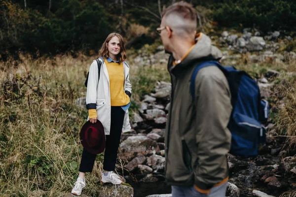 Lovely couple travelling together in the mountains, walking around the lake Morskie oko in Tatry. Relaxed traveller high in the mountains. Appeasement in the nature. Man in glasses and a gray jacket.