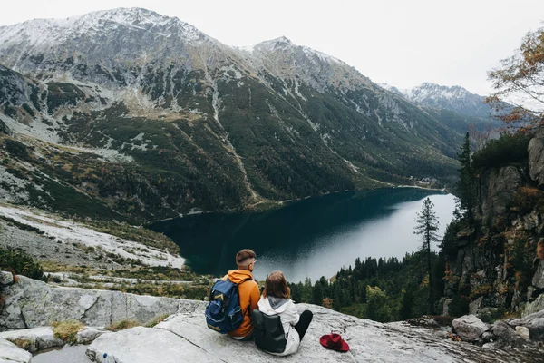 Lovely couple travelling together in the mountains, walking around the lake Morskie oko in Tatry. Amazing girl in a white jacket. Stunning view.