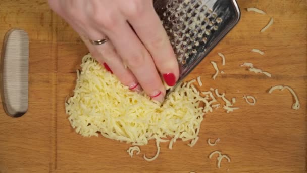 女人在厨房的桌子上格奶酪。女性双手格栅奶酪特写镜头. — 图库视频影像