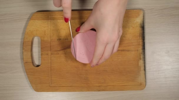 Kvinnans händer skära en kokt korv på skivor. — Stockvideo