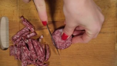 Sosis kesme tahtası üzerinde dilimleme. Sığır sosis. Bir mutfak bıçağıyla kesilmiş.