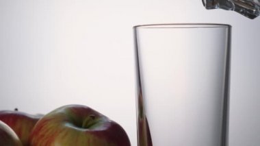 Elma suyu şeffaf bir cam yakın çekim yavaş hareket içine dökülür