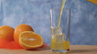 Portakal suyu yavaş harekette buz ile berrak bir bardağa dökülür