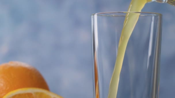 O suco de laranja é derramado em um vidro transparente com um close-up em câmera lenta — Vídeo de Stock