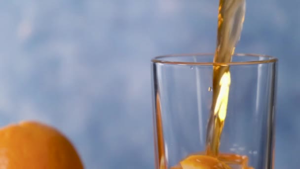 La limonada naranja amarilla se vierte en un vaso transparente con naranja y hielo. Movimiento lento . — Vídeo de stock