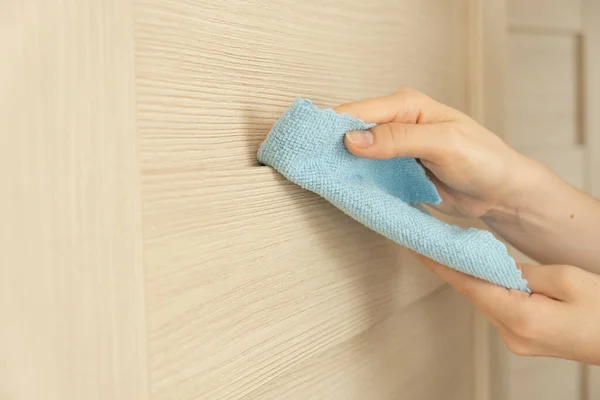 Las manos femeninas sostienen un trapo para limpiar. Limpie las superficies y manijas de las puertas. — Foto de Stock