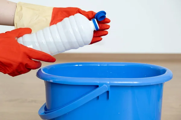 Manos en guantes para la limpieza de un limpiador para limpiar superficies sobre un cucharón azul.. — Foto de Stock