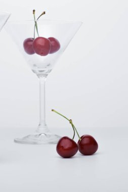  Martini bardağında kiraz. Ekran koruyucu için yakın çekim. Yakınlarda bir kiraz yatar.