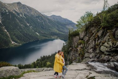 Young couple in yellow raincoats on walk inTatra Mountains near lake Morskie Oko, Poland clipart