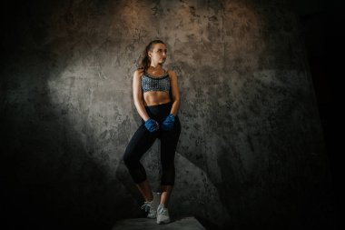 young beautiful girl boxer in a dark gym