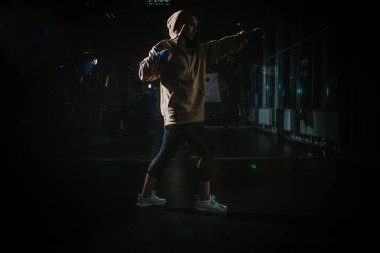 young beautiful girl boxer in a dark gym