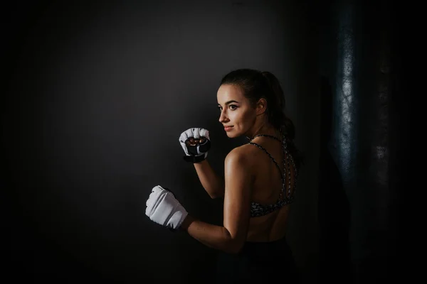 young beautiful girl boxer in a dark gym