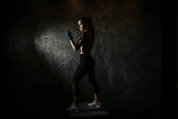 young beautiful girl boxer in a dark gym