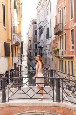 Venedik dar kanal üzerinden köprüde poz çekici Kızıl saçlı kadın