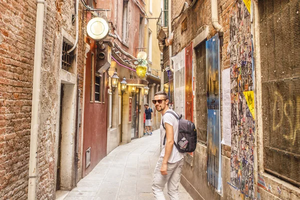 Boş Arnavut kaldırımlı sokakta yürüyen sırt çantası ile genç adam