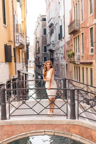 Venedik dar kanal üzerinden köprüde poz çekici Kızıl saçlı kadın